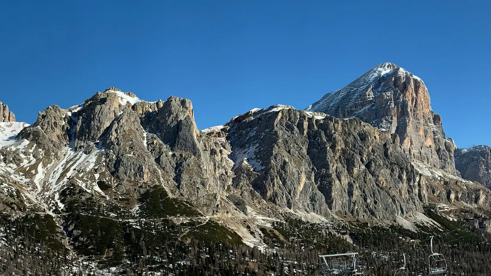 La Tofana di Rozes innevata sopra il bosco, con una seggiovia in primo piano