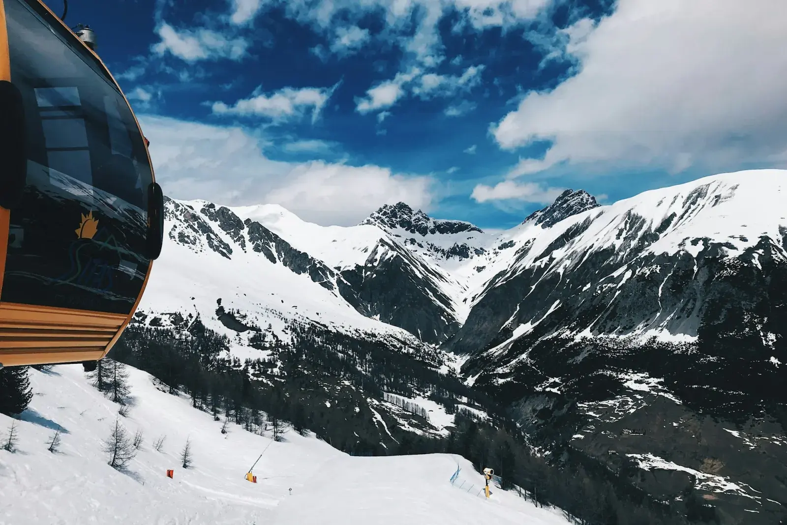Cabina della cabinovia sopra le piste di Livigno, con le montagne innevate