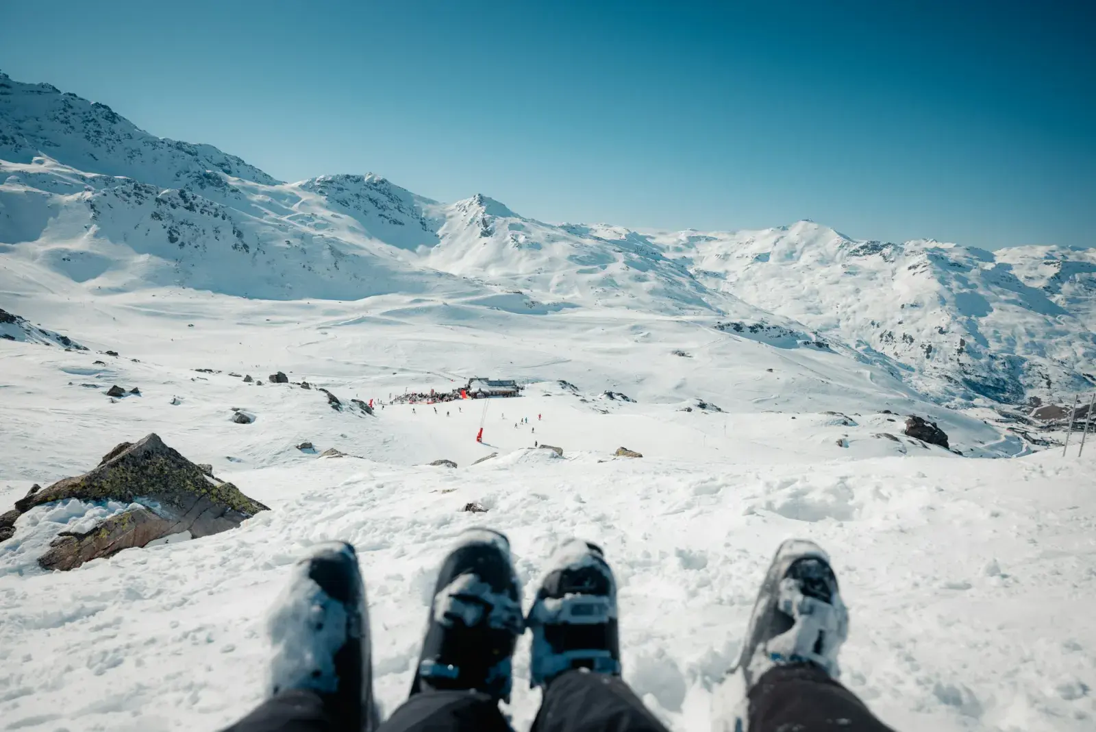 Scarponi da sci ai piedi, visti dall'alto, sulla neve davanti alle piste