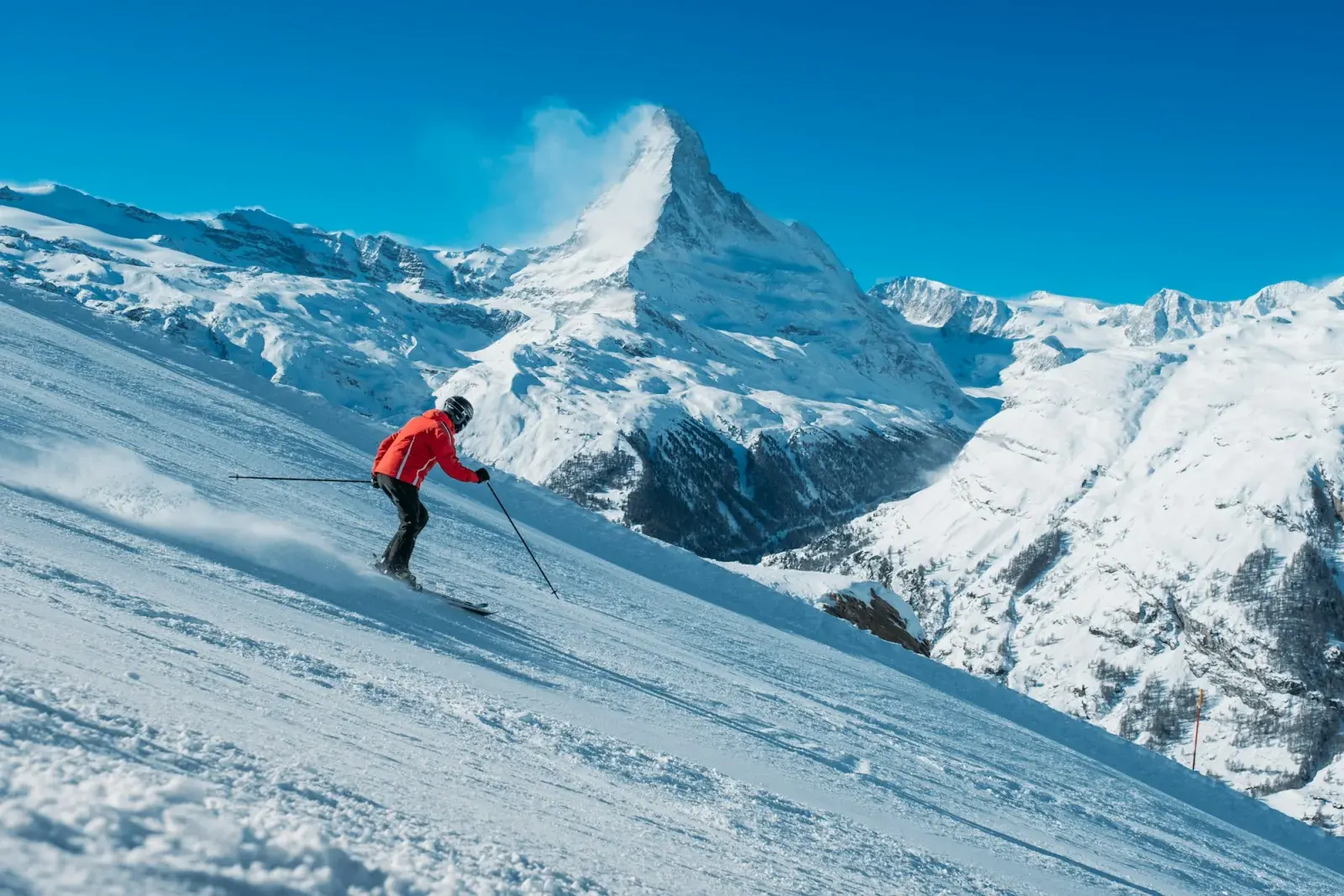Sciatore su una pista battuta in una giornata di sole, con il Cervino sullo sfondo
